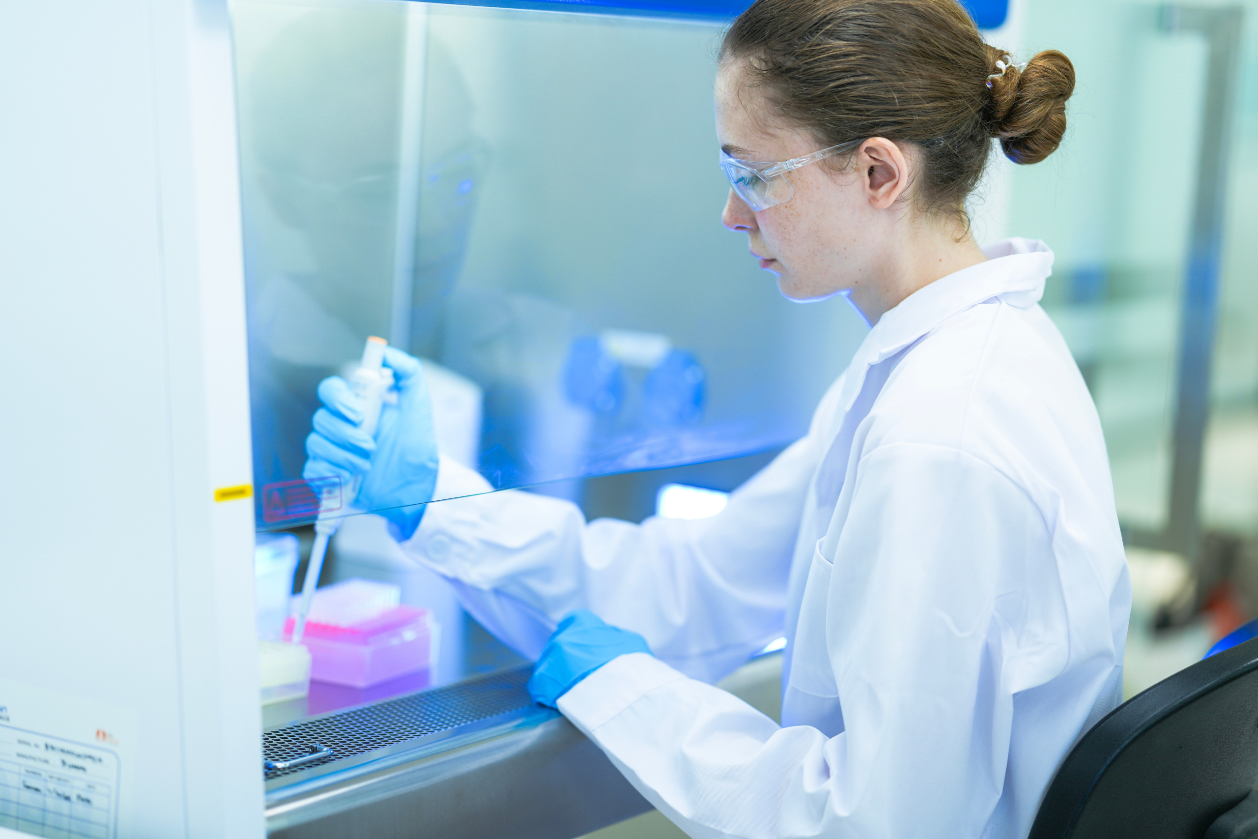Scientist pipetting in a safety hood